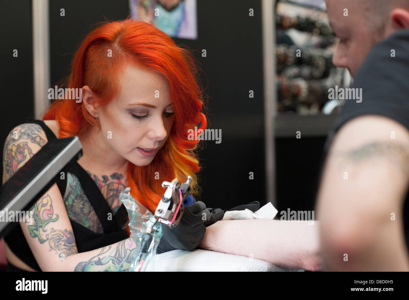 US model and tattooist, Megan Massacre from New York, works on a male at the Great British Tattoo Show, London, UK. Stock Photo