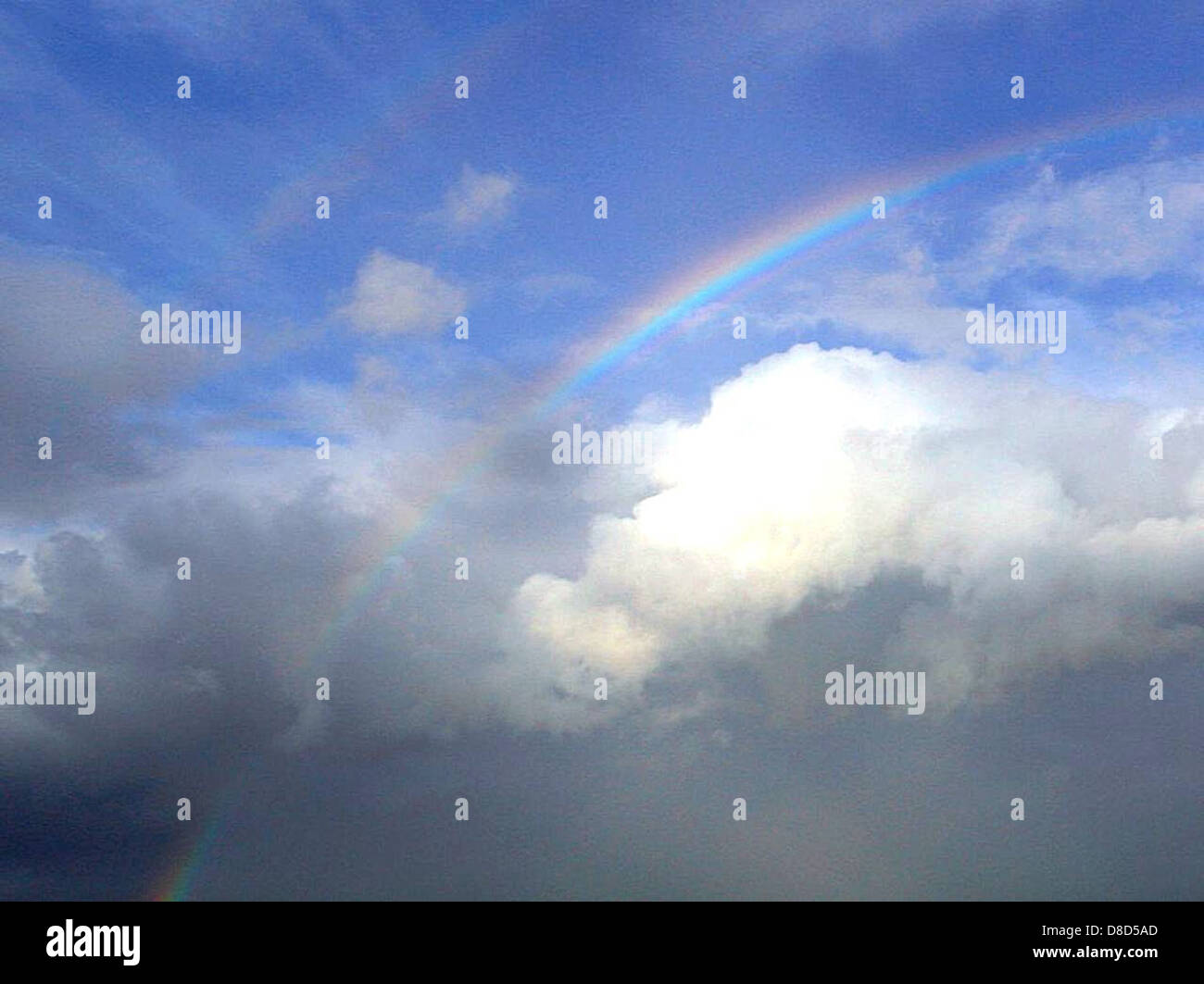 A vibrant rainbow arching across the sky, with fluffy white clouds in ...