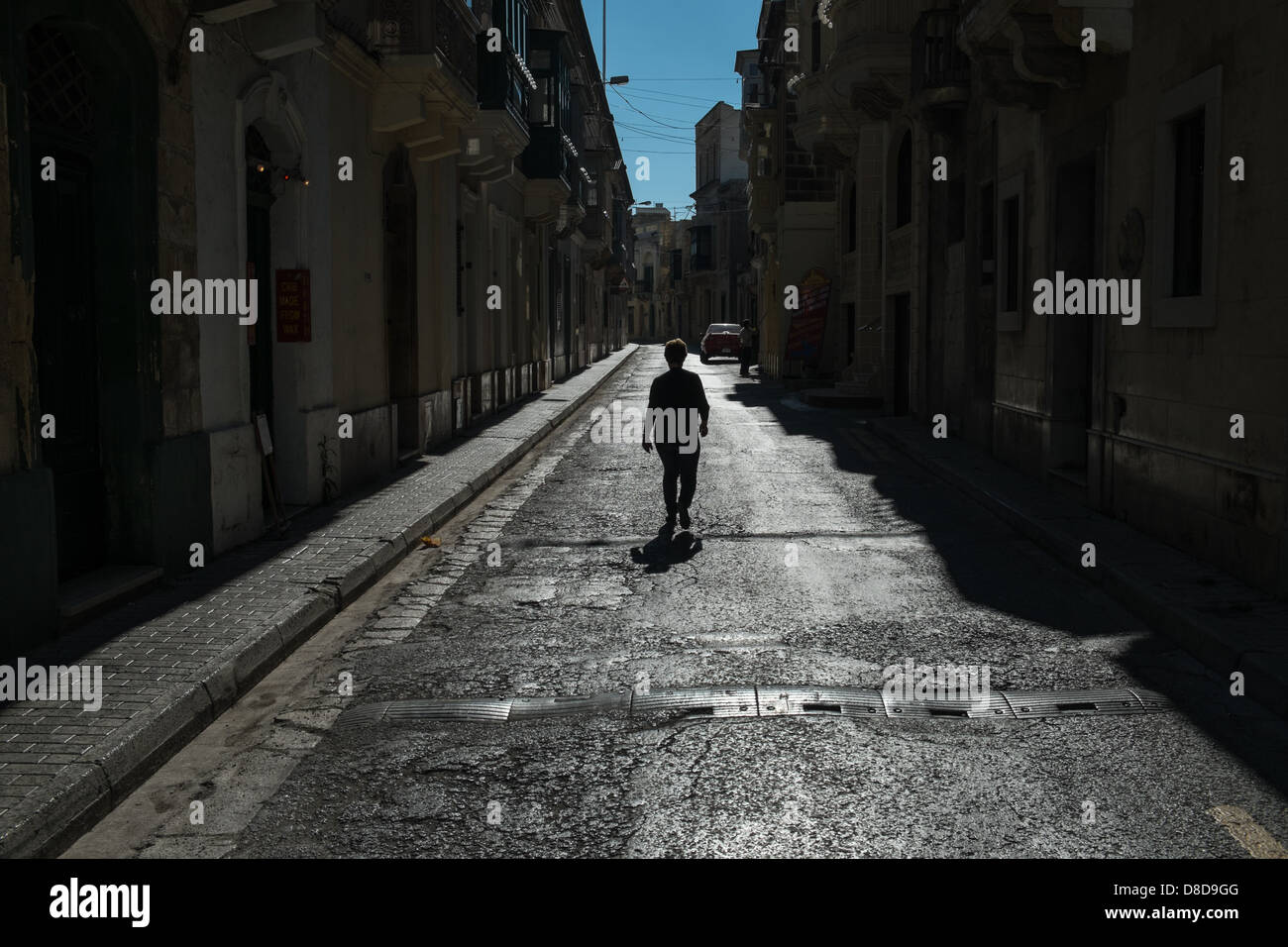 A lone woman walks down the center of a residential street in Gozo's