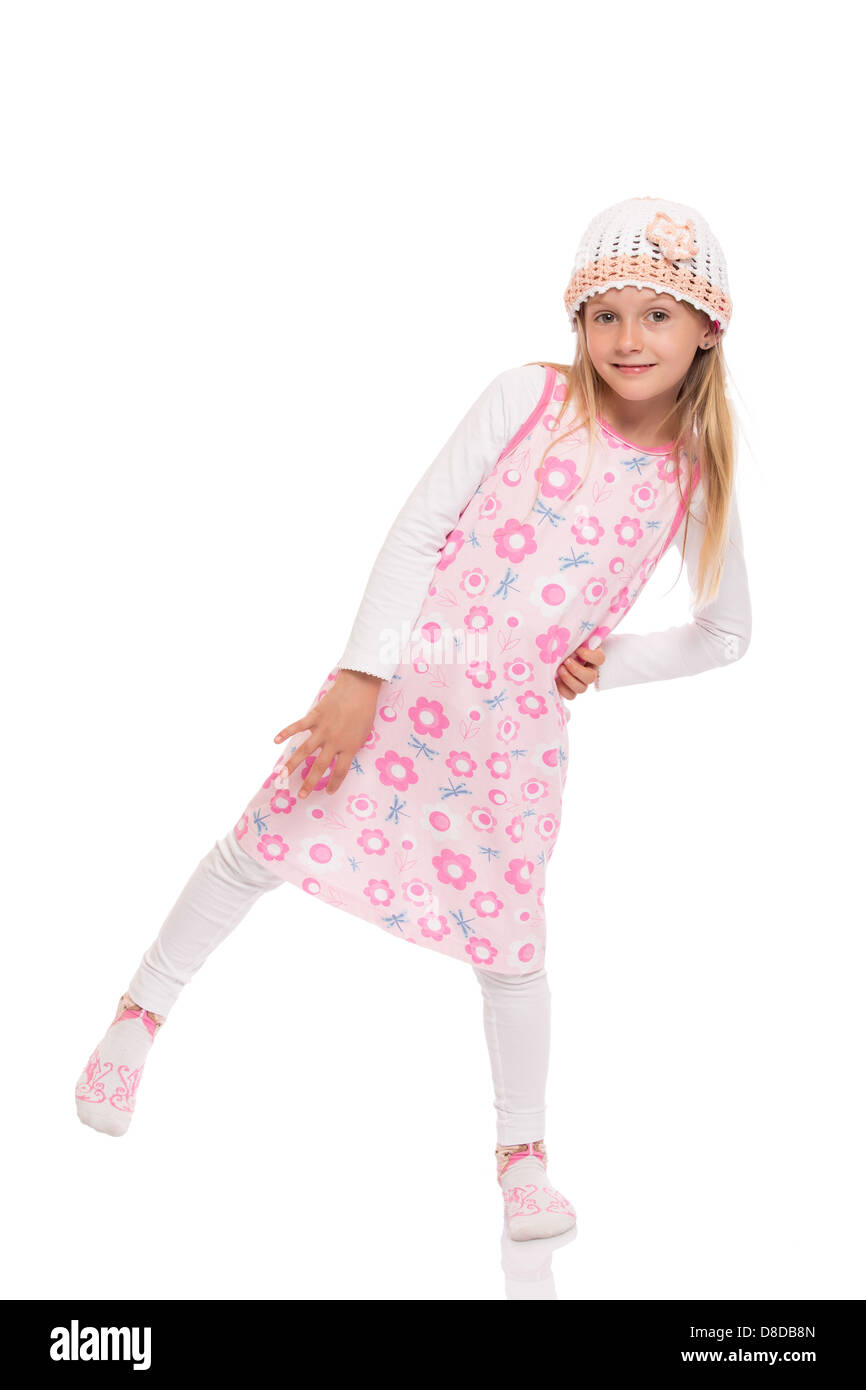 Full length portrait of a little girl with long hair wearing summer dress, knit cap and balancing at one leg. Stock Photo