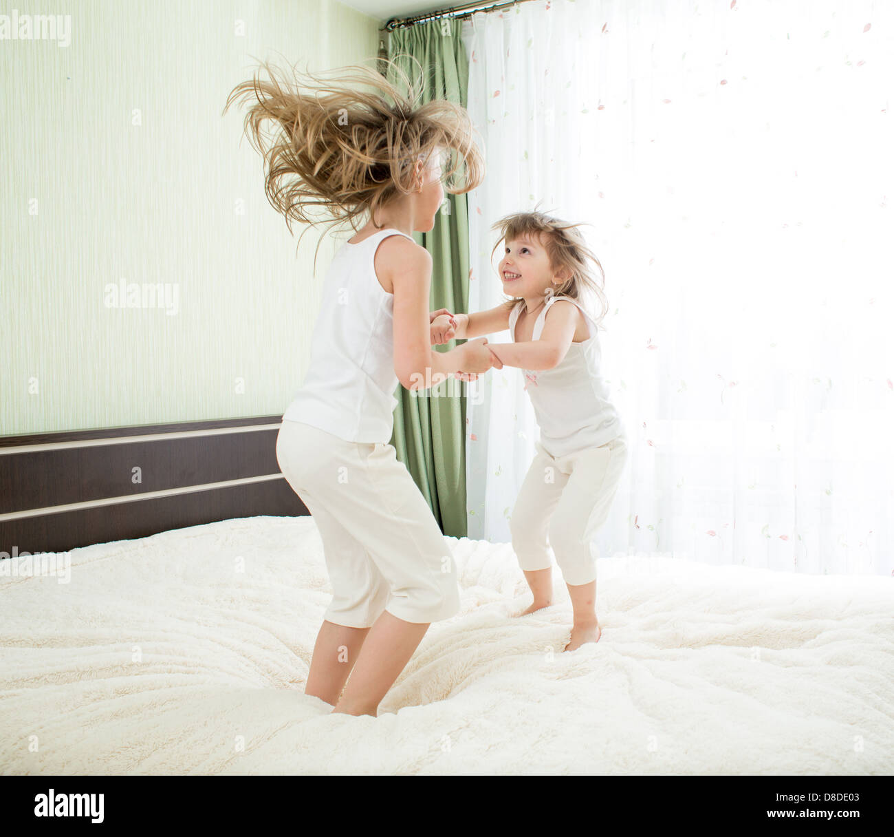 Little girls jumping on bed Stock Photo
