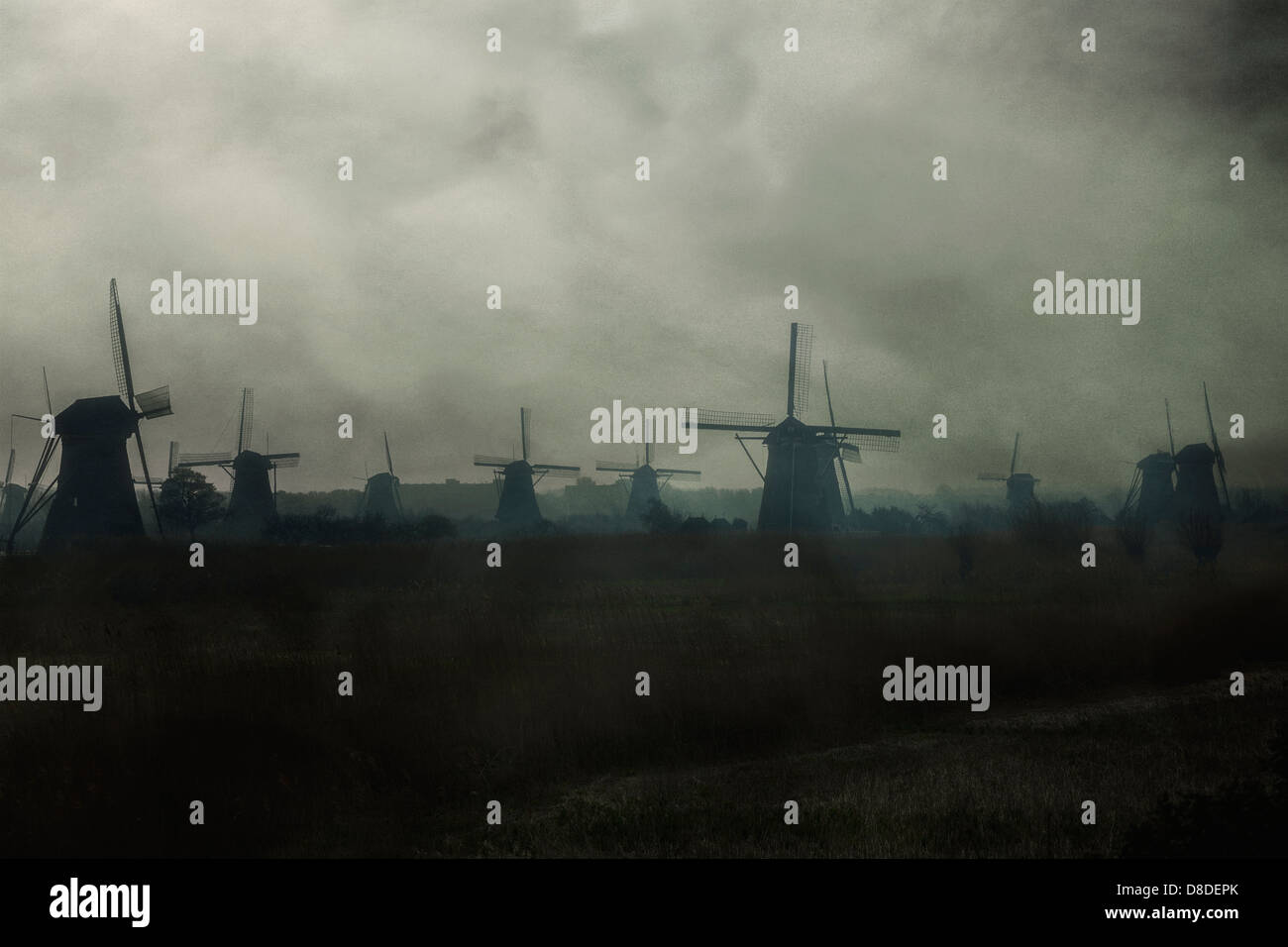 many windmills on a field in morning mist Stock Photo