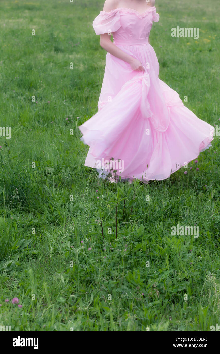 a woman in a pink dress is dancing on a meadow Stock Photo - Alamy