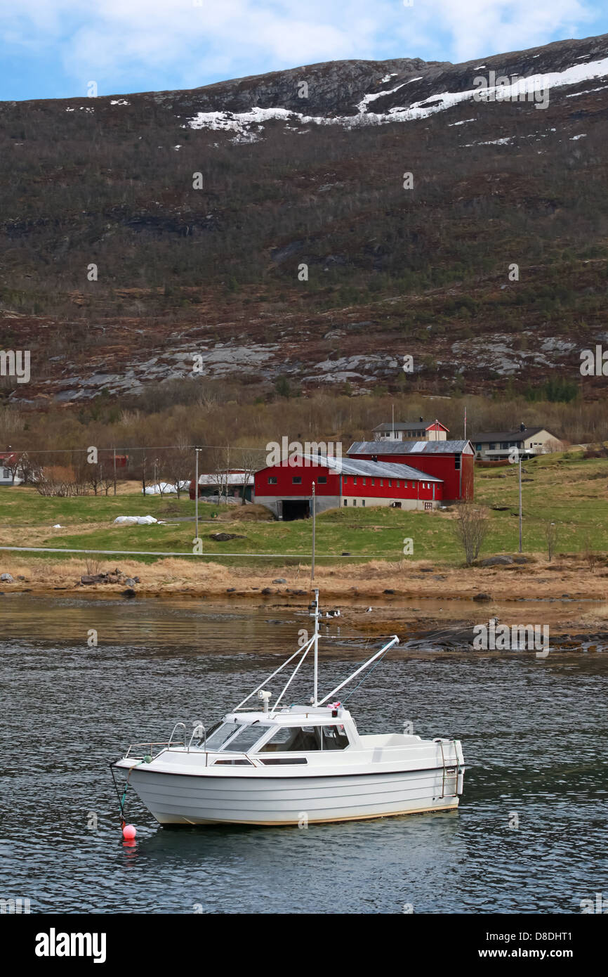 Small white motor boat moored in Norway nearby small village Stock Photo