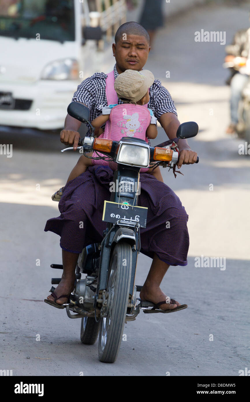 Chaotic road traffic on Mandalay roads, Myanmar 3- sleepy moped rider with baby Stock Photo