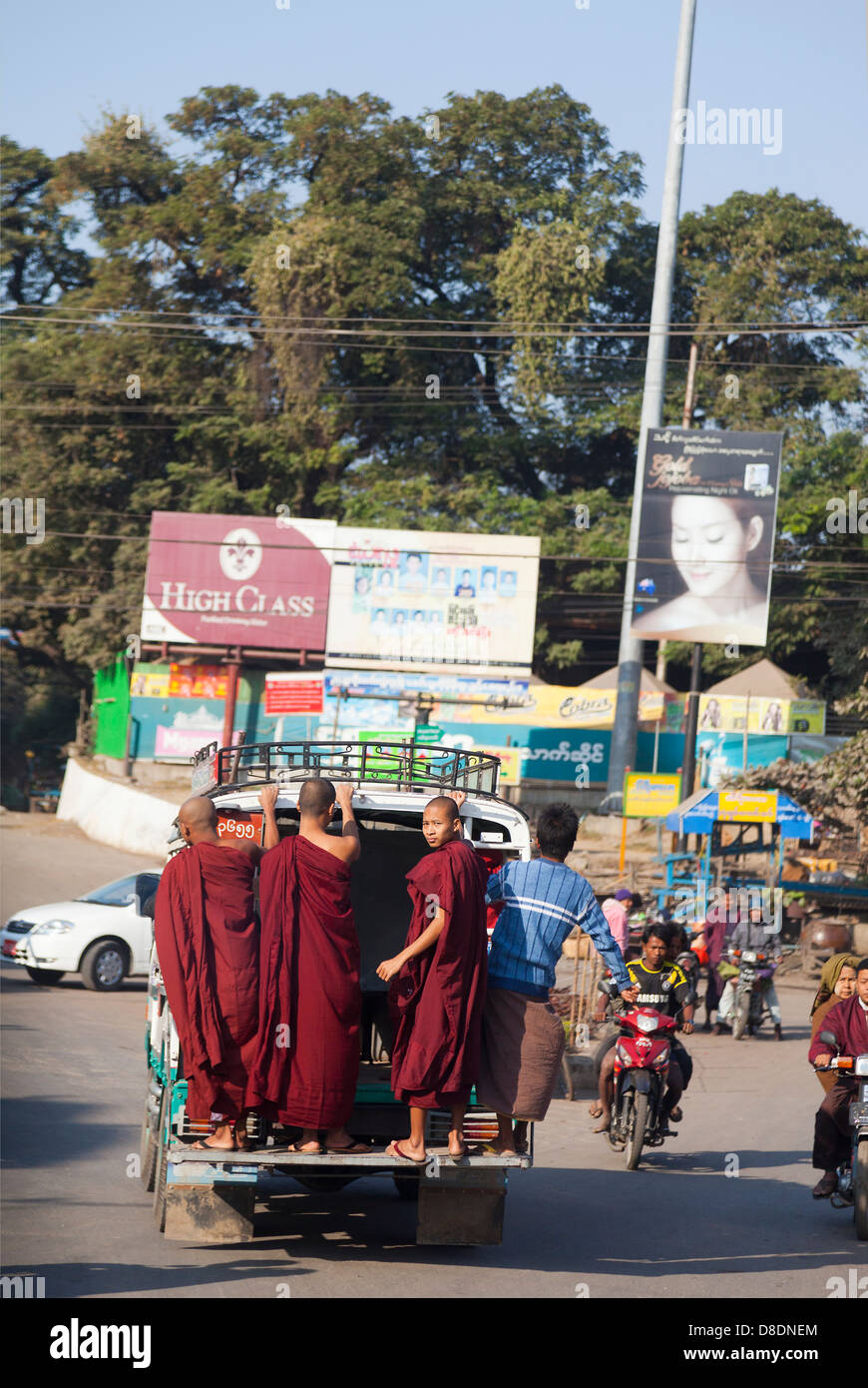 Monks hanging off the back end of a pickup truck in Mandalay, Myanmar Stock Photo