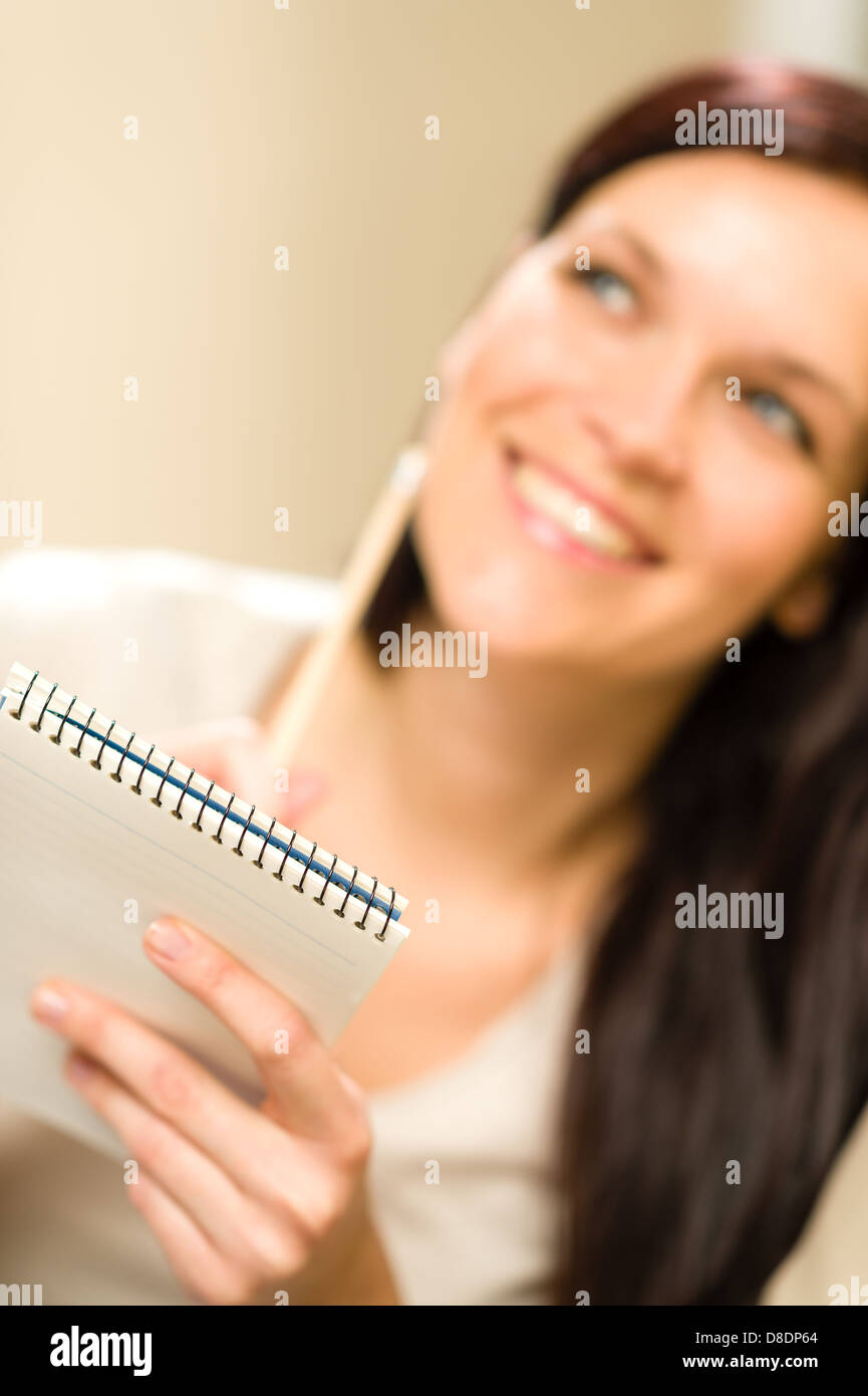 Smiling thinking woman holding notepad looking for inspiration Stock Photo