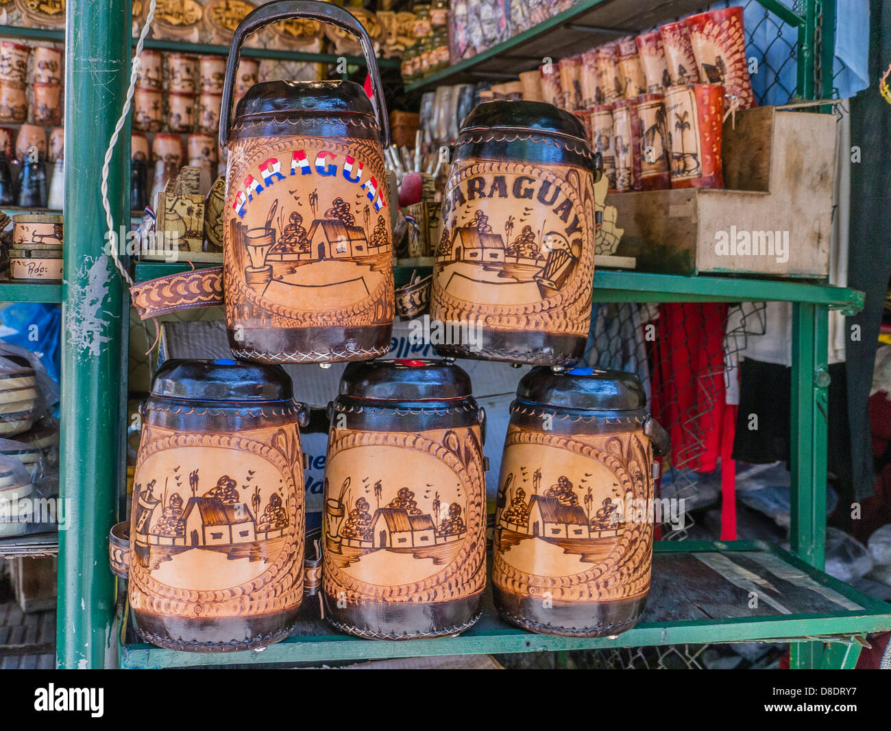 Tooled leather thermos bottles on display for sale at a vendor's stall