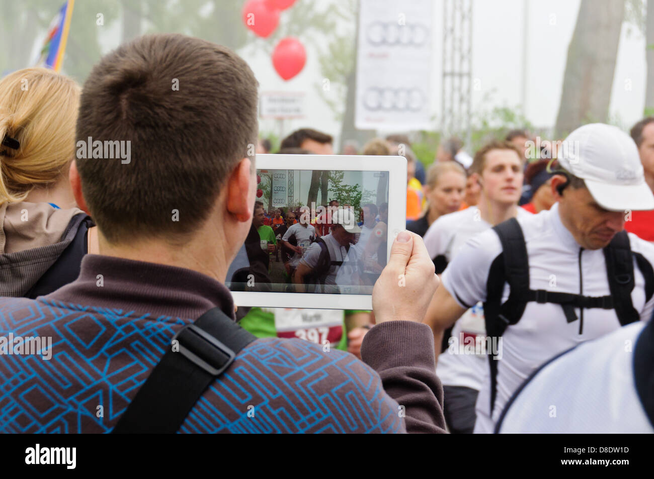 Man with an Apple iPad films marathon runners at the annual Trollinger-Marathon in Heilbronn, Germany Stock Photo