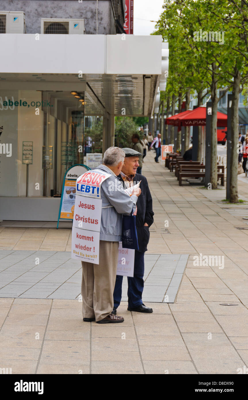 Old Christian missionary, preacher man, evangelizes a male senior citizen on the street – Heilbronn, Germany Stock Photo