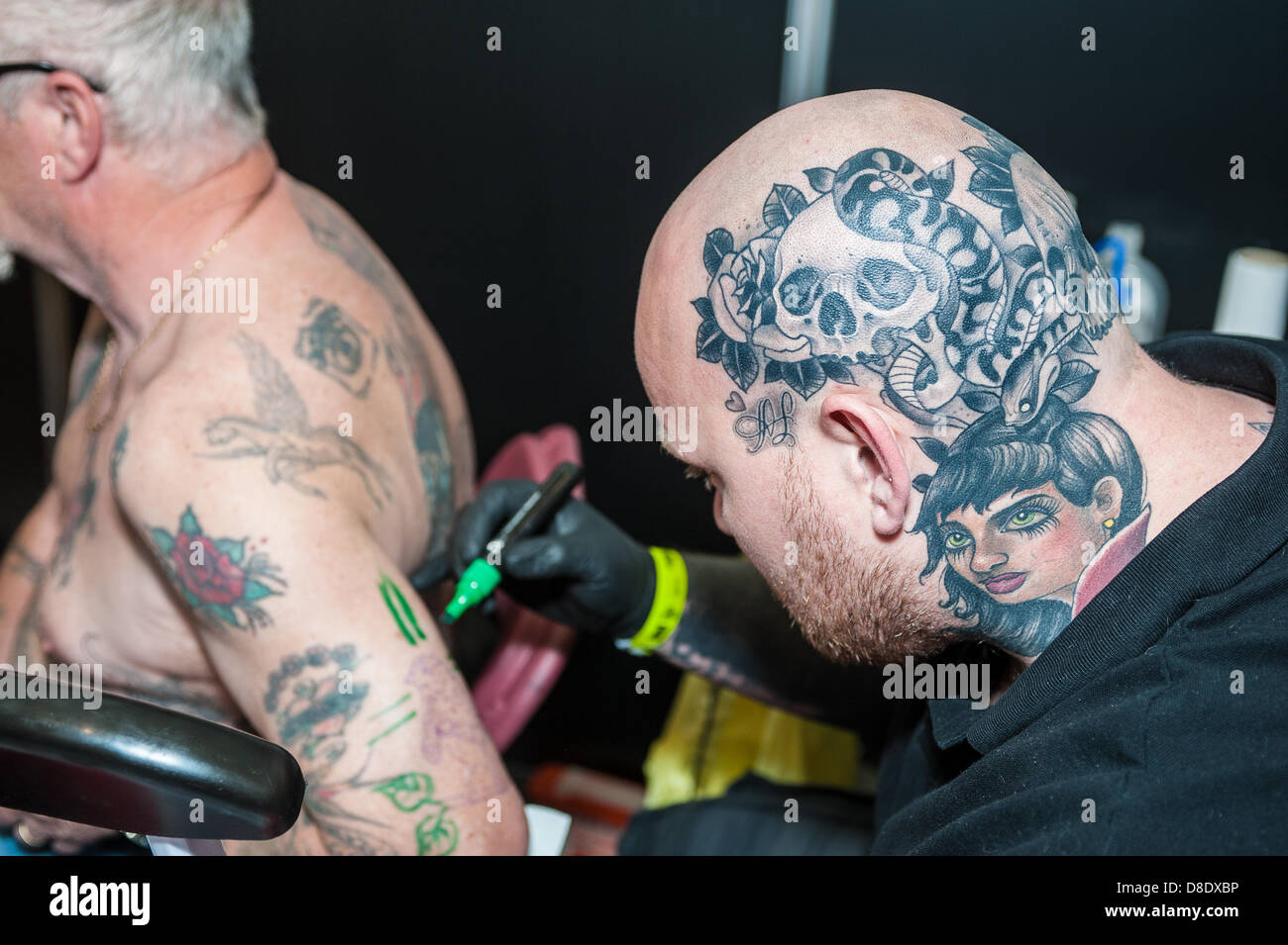 London, UK, 26th May 2013. Tattooist Gez Bradley (right), 28 from Gosport, Hampshire, designing a tattoo on the arm of his father Mervin, 62, also from Gosport. Mervin's occupation is laser tattoo removal. Credit: /Alamy Live News Stock Photo
