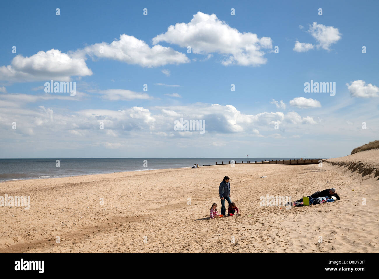 A family sitting on the sand on deserted Horsey Beach, Norfolk, East anglia England UK Stock Photo