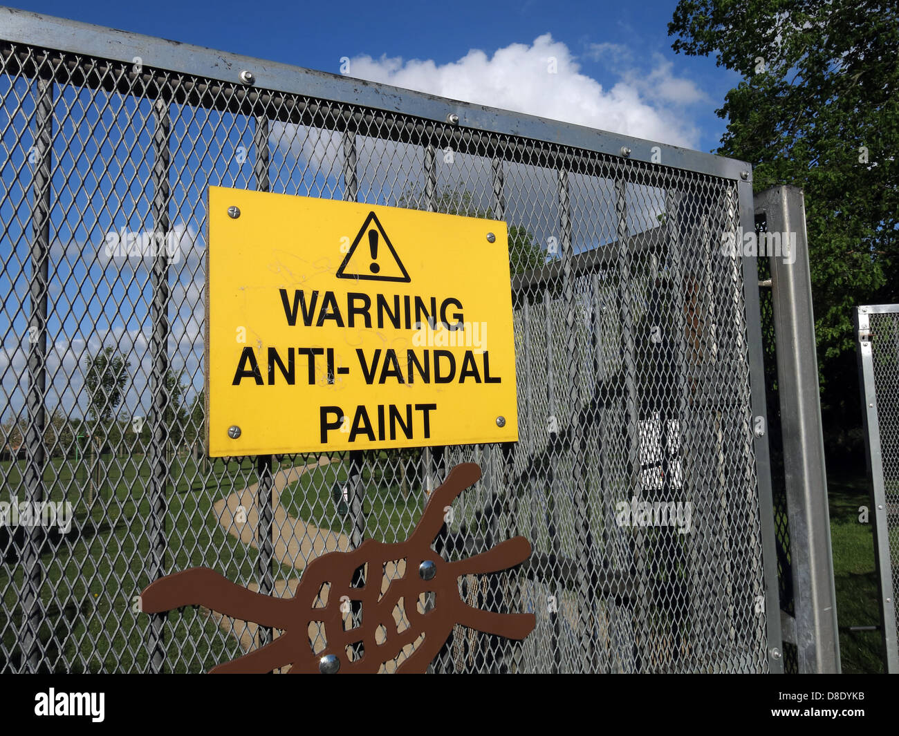 Yellow Warning Anti-Vandal paint sign on a playground gate , Grappenhall  Warrington  Cheshire England UK Stock Photo
