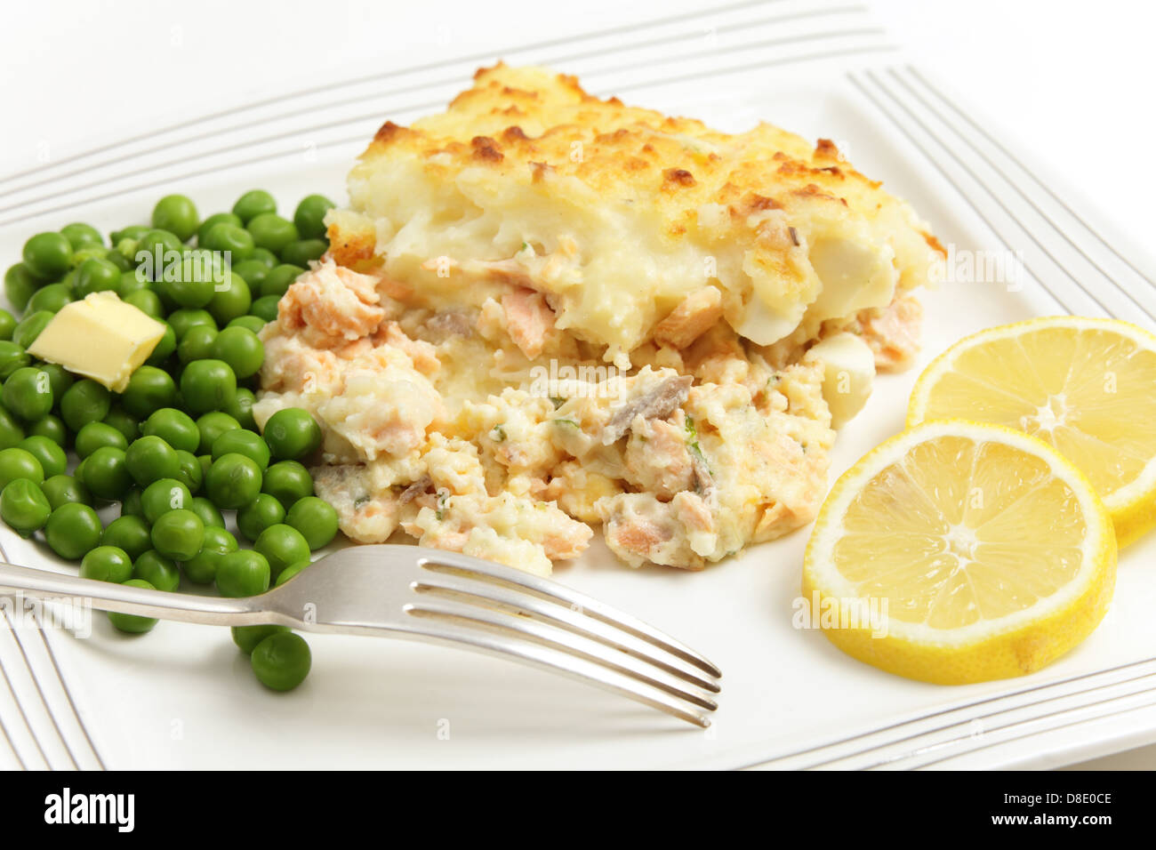 Homemade salmon, egg and potato pie, served with boiled peas and garnished with slices of lemon Stock Photo