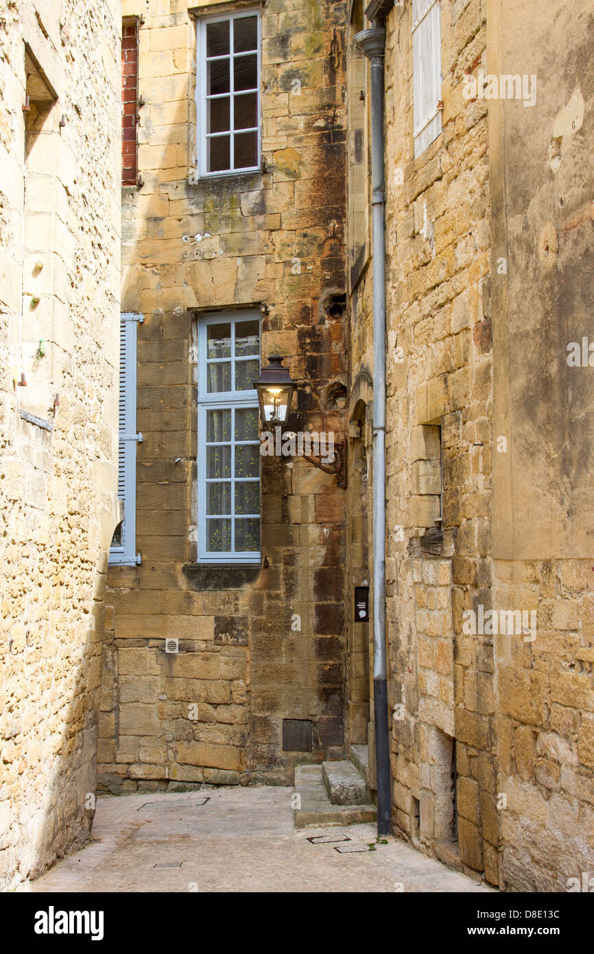 Narrow cobblestone street among medieval sandstone buildings in charming Sarlat, Dordogne region of France Stock Photo