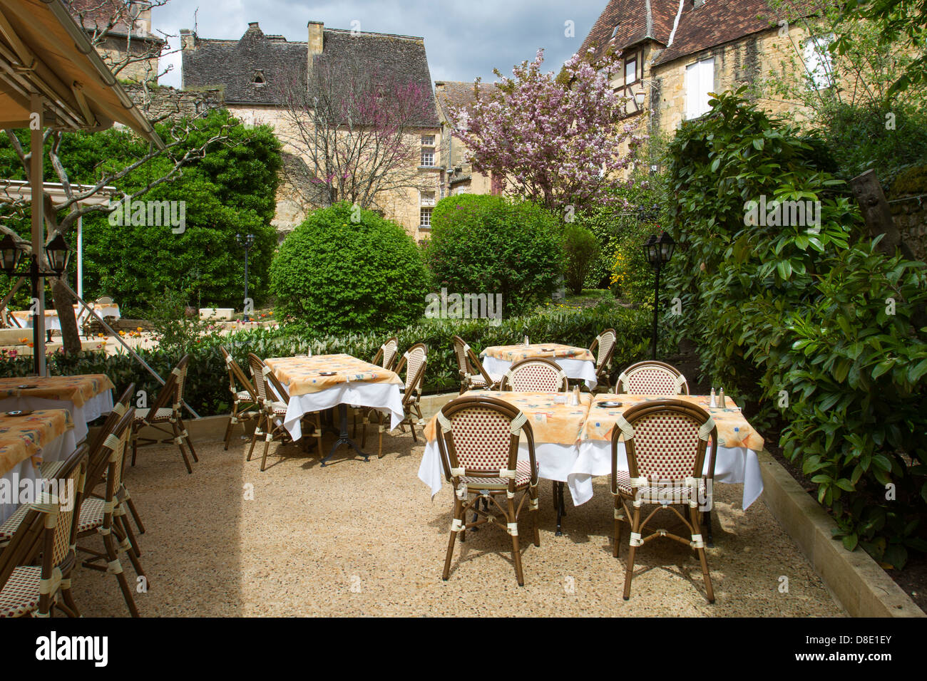 Outdoor courtyard dining at a restaurant by medieval sandstone buildings in charming Sarlat, Dordogne region of France Stock Photo