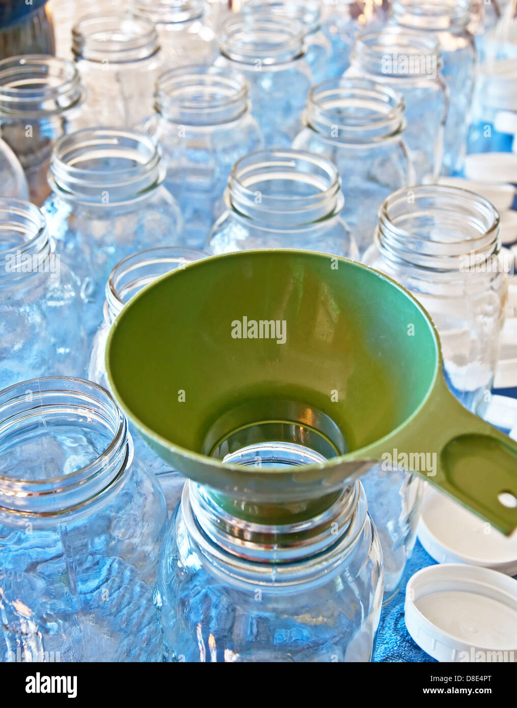 Clean canning jars in quart size with a green funnel in preparation for