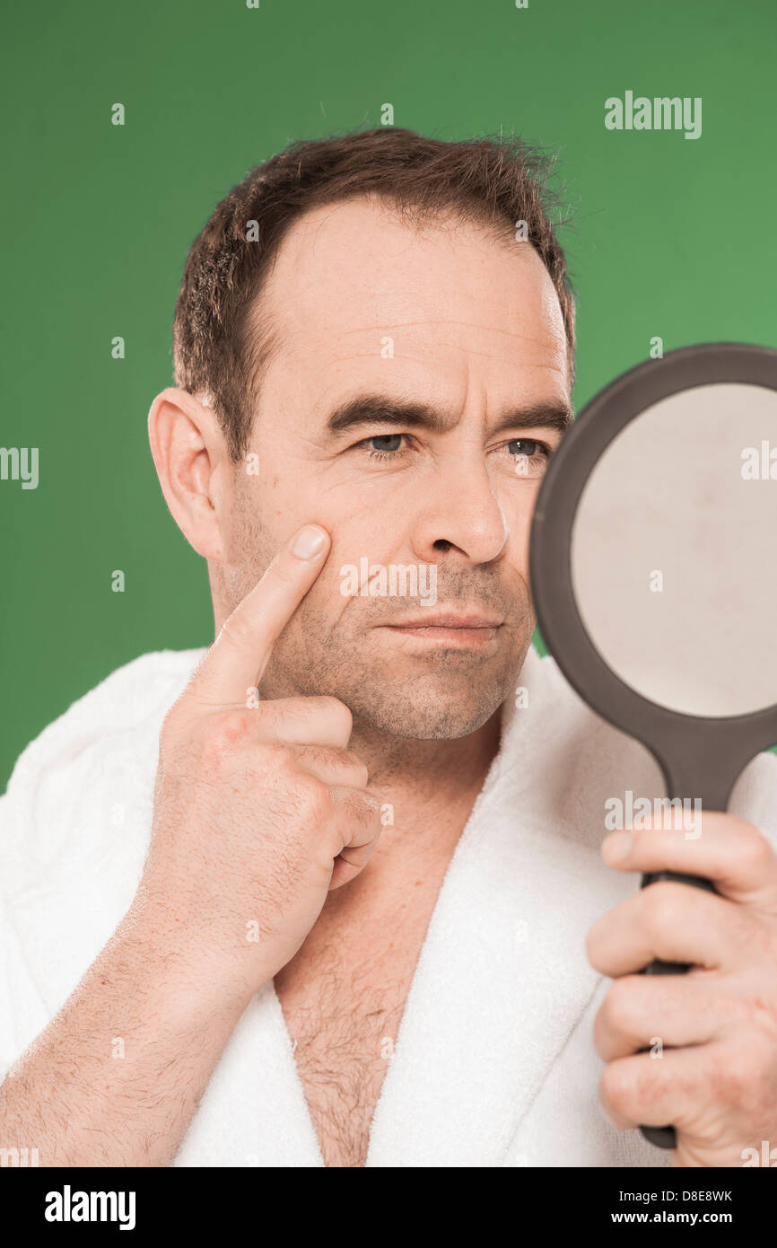 Man in bathrobe looking in make-up mirror Stock Photo