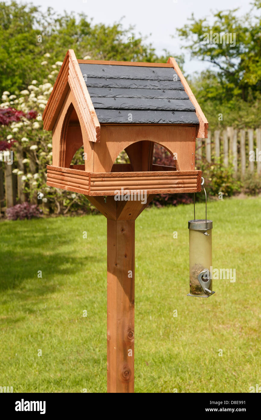 Wooden Bird Table With Slate Roof And A Seed Feeder In A Domestic
