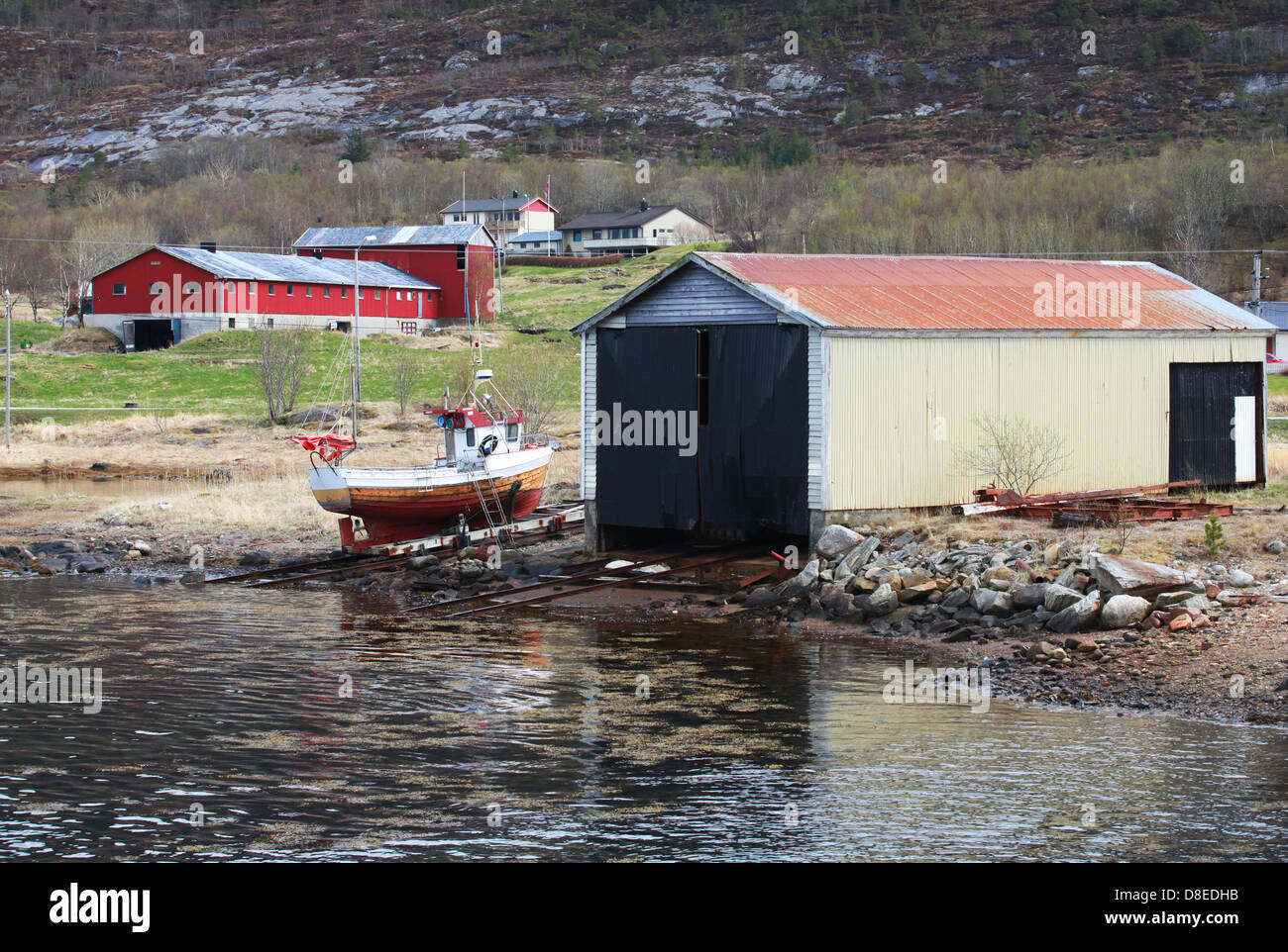 Traditional Norwegian wooden barns and small fishing boat on the sea coast Stock Photo