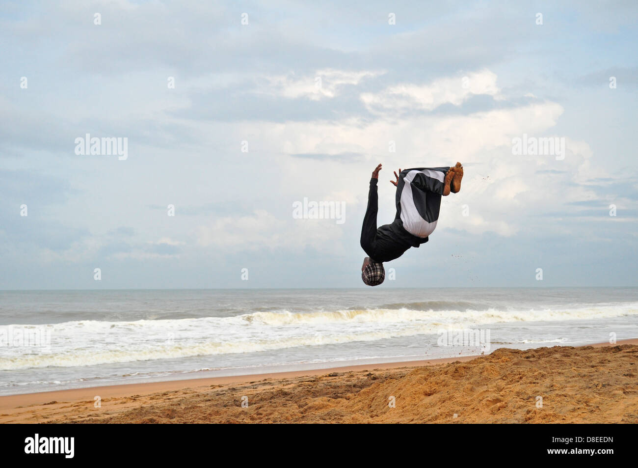 An acrobat practices on the beach Stock Photo