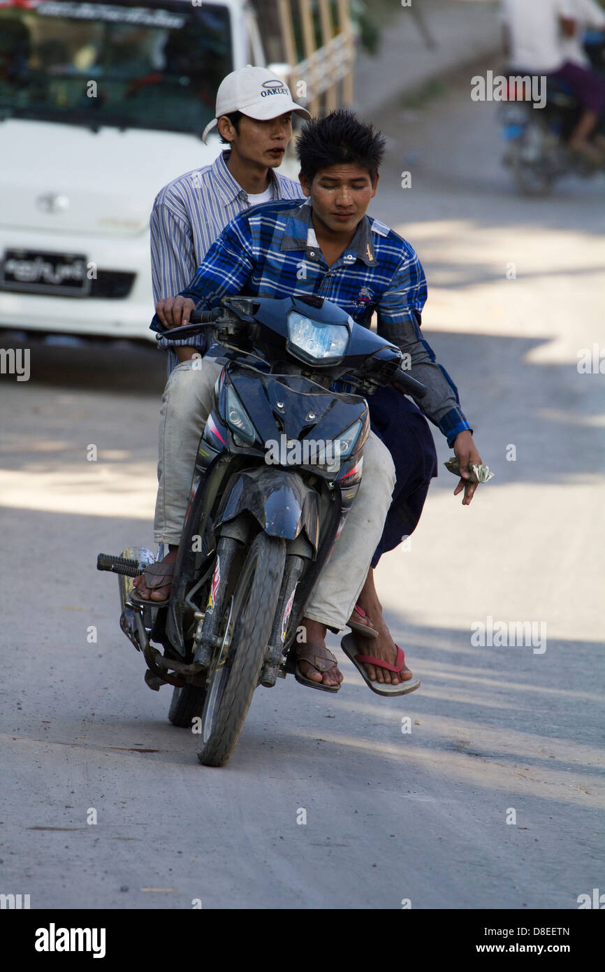 Chaotic road traffic on Mandalay roads, Myanmar 8- moped rider unwilling to let go of a fistfull of dollars Stock Photo