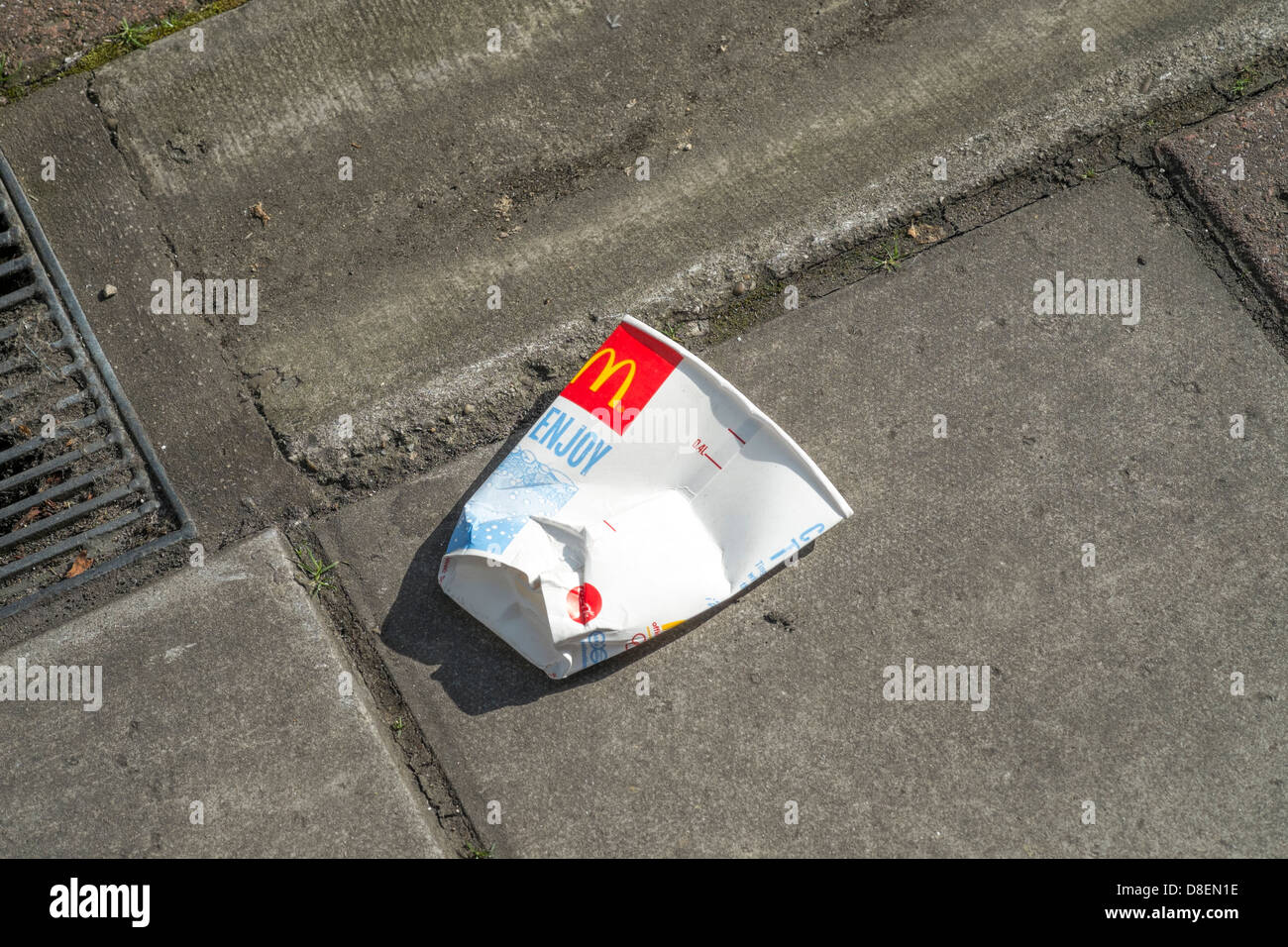 Discarded and crushed McDonalds paper cup on the pavement Stock Photo