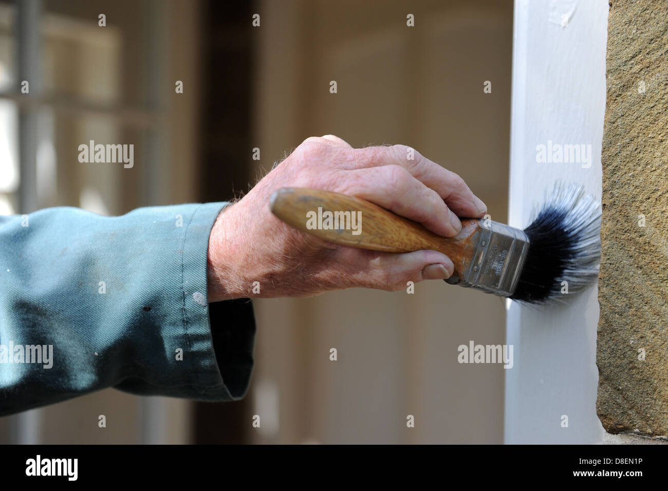 Elderly male painting the door frame on the porch of his house Stock
