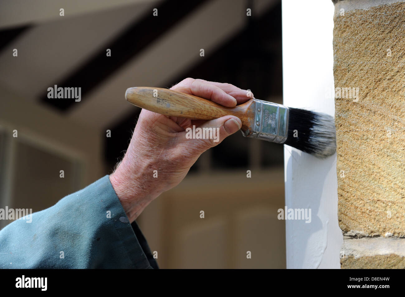 Elderly male painting the door frame on the porch of his house Stock