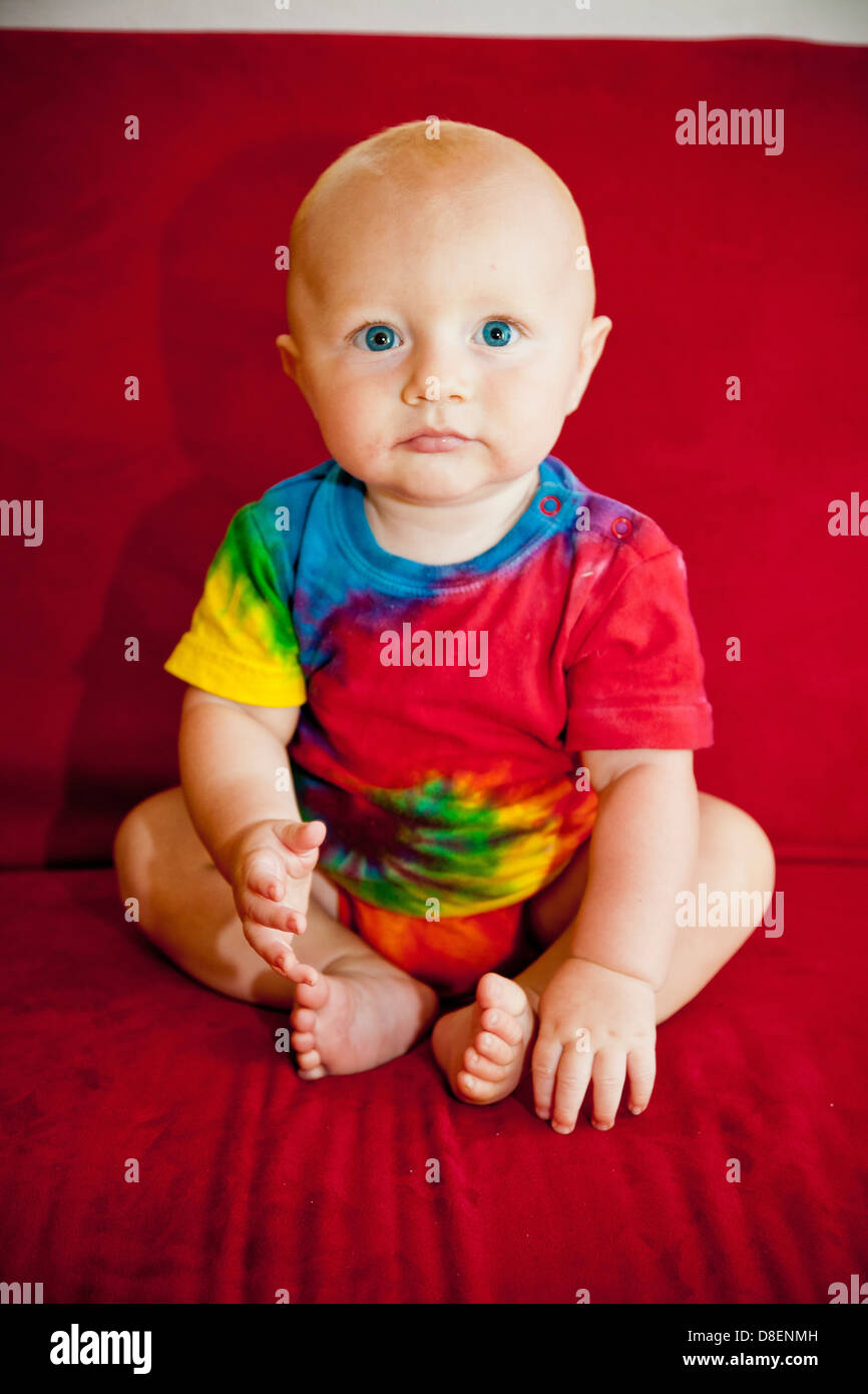 Baby boy sitting on red sofa Stock Photo
