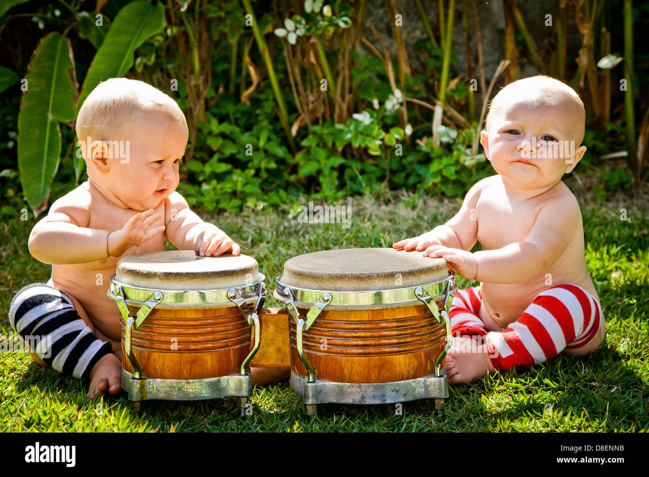 Twin babies playing drums outdoors Stock Photo