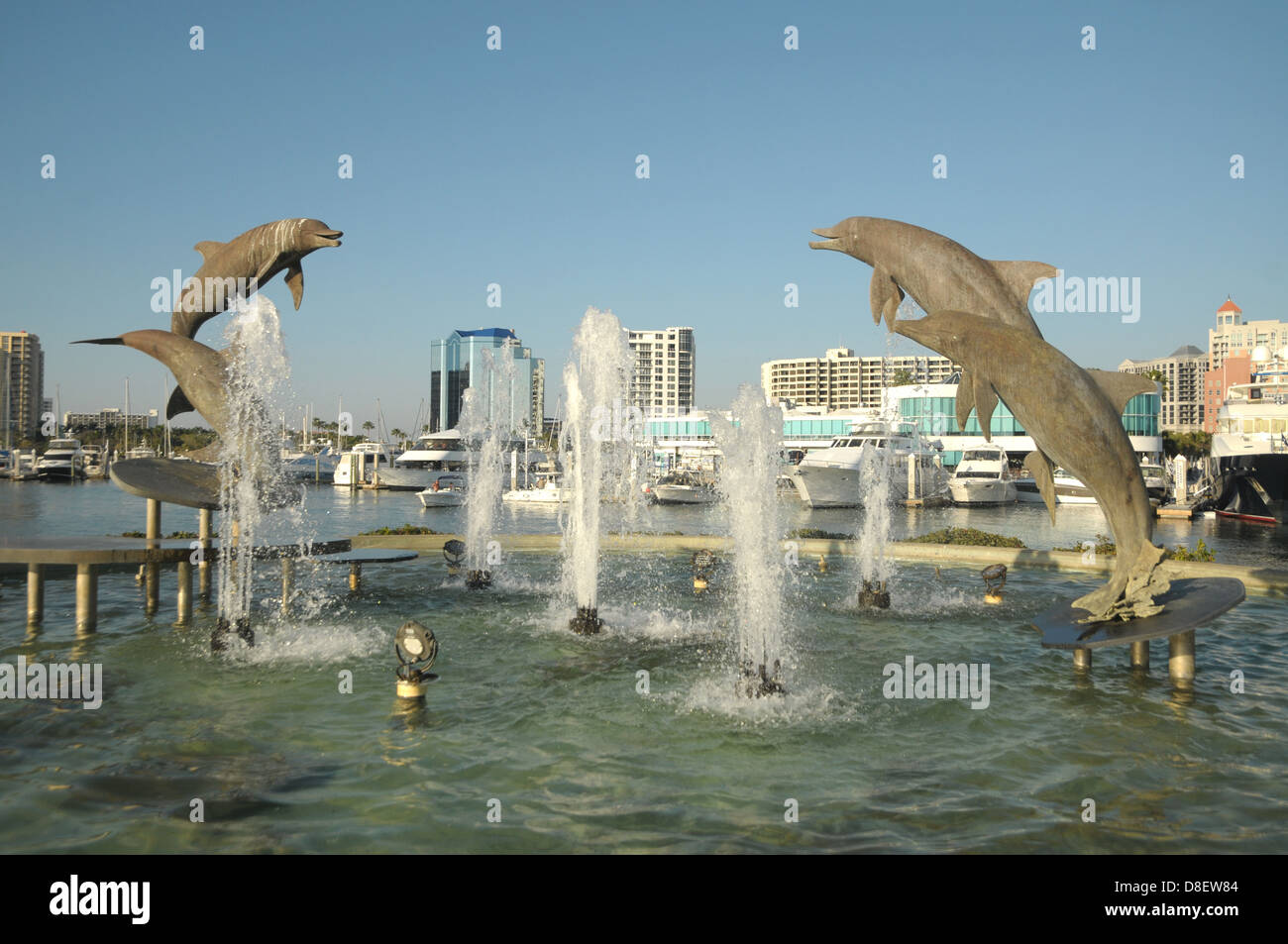 Dolphin statues show themselves in the air at a water fountain at Sarasota, FL by the waterfront. Stock Photo