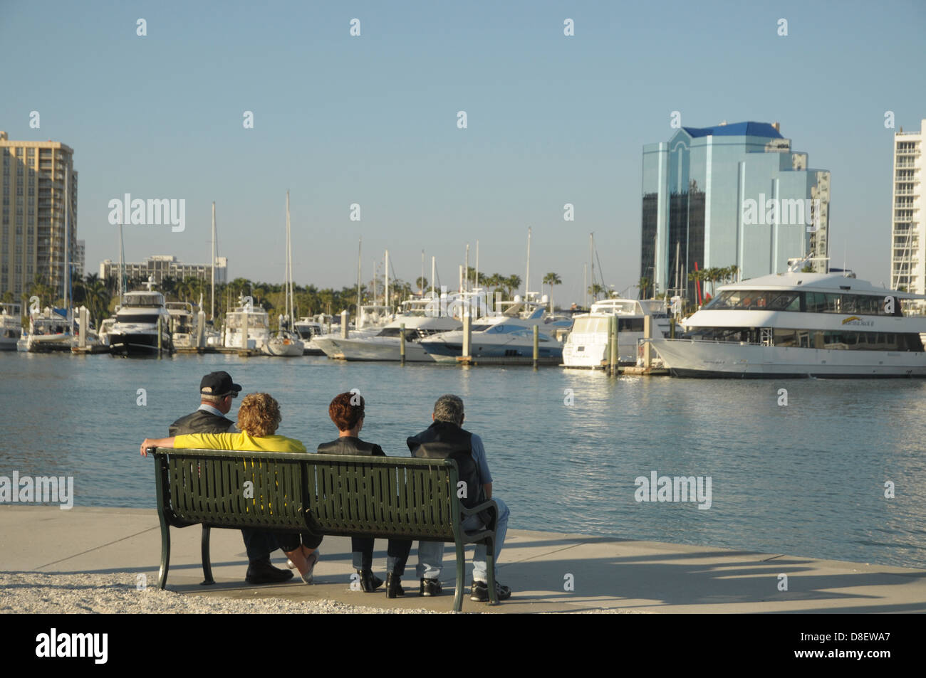 A group of people sit on a bench at the Sarasota, Florida waterfront. Stock Photo