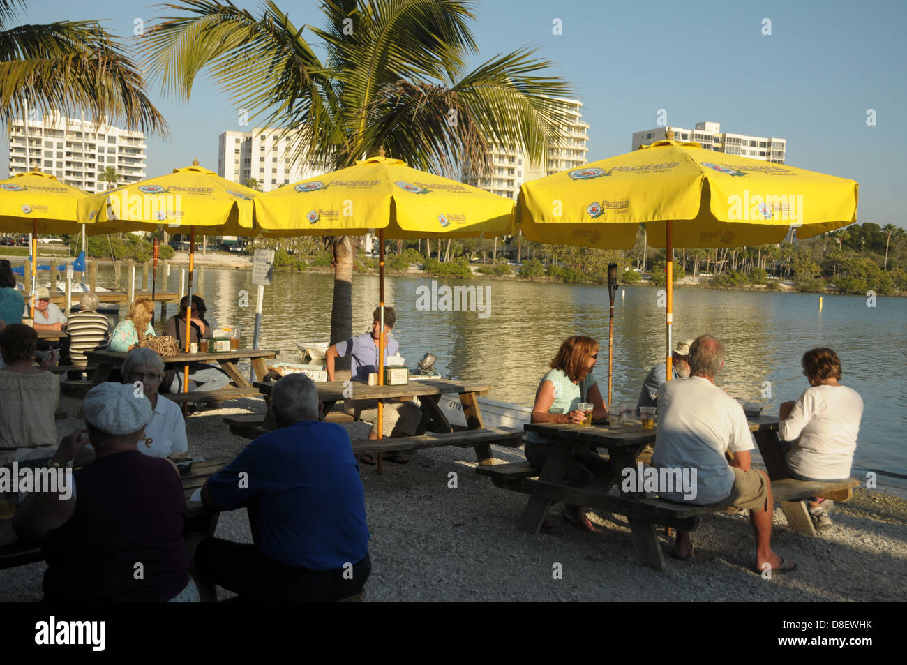 People sit by umbrellas at a bar as the sky line of Sarasota graces the background. Stock Photo