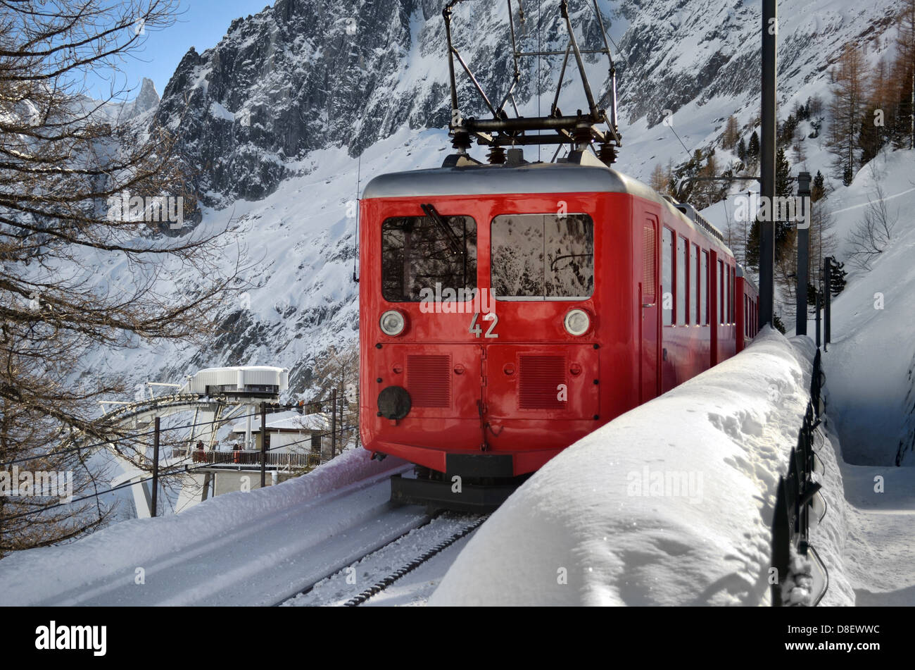 Small, red mountain train climbing railway in the snow Stock Photo