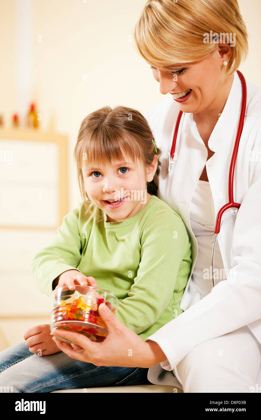 Female pediatrician doctor giving candy (gummy bears) to little patient