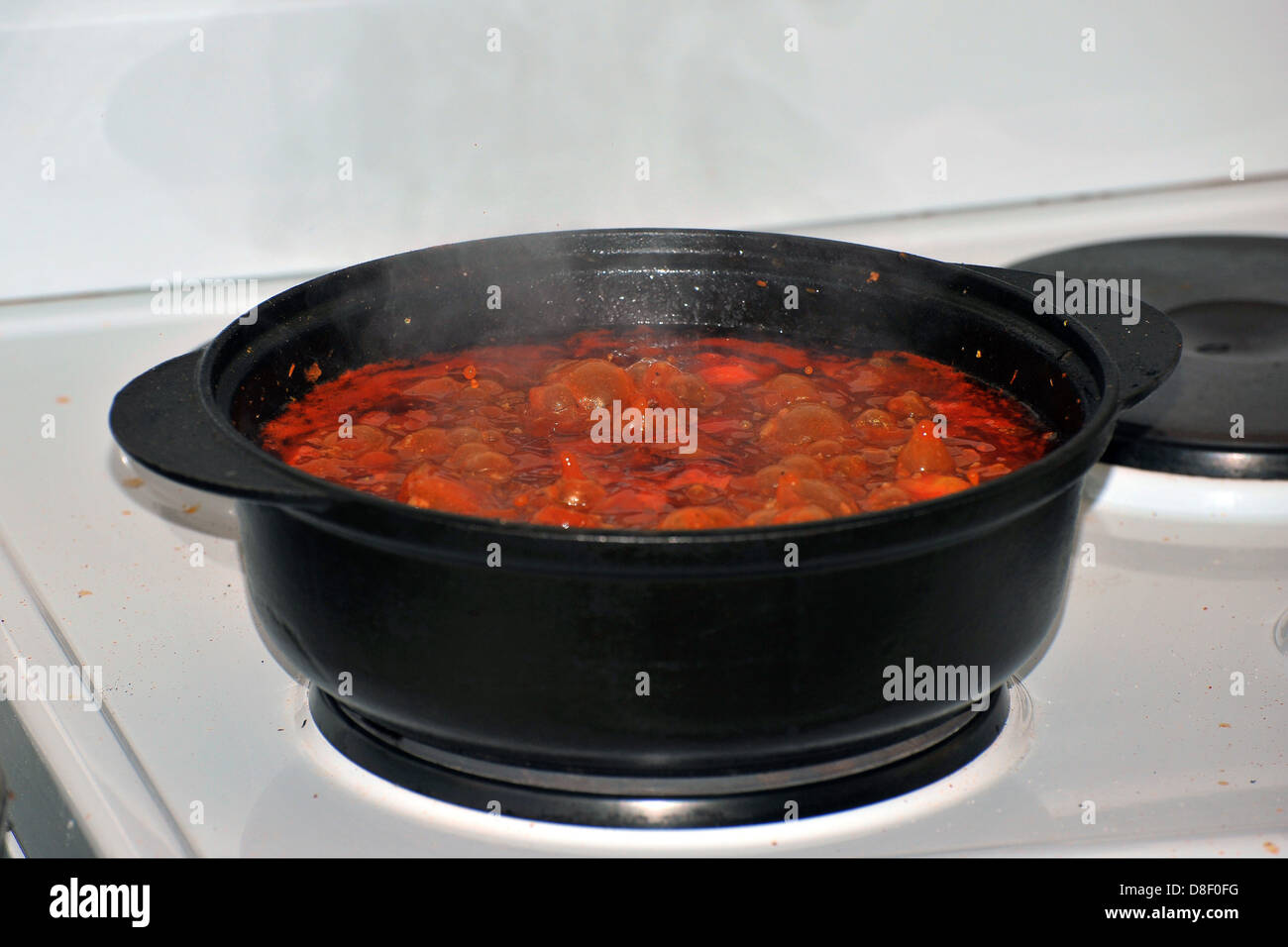 Images of a stew cooking in a cast iron pot on an electric cooker. Stock Photo