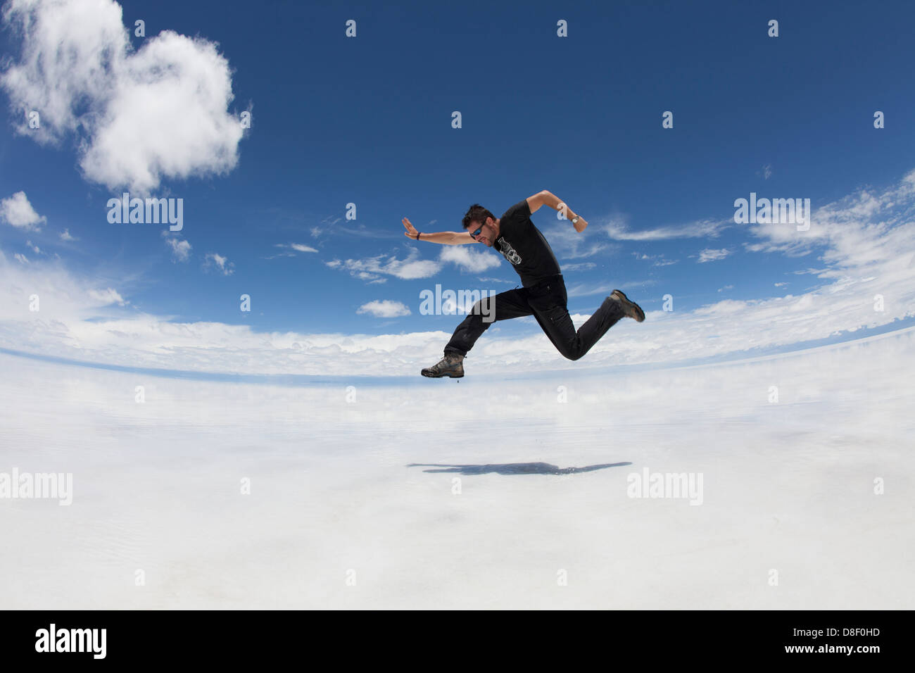 Man jumping in mid air with clear dreamlike landscape (Salar de Uyuni) Stock Photo