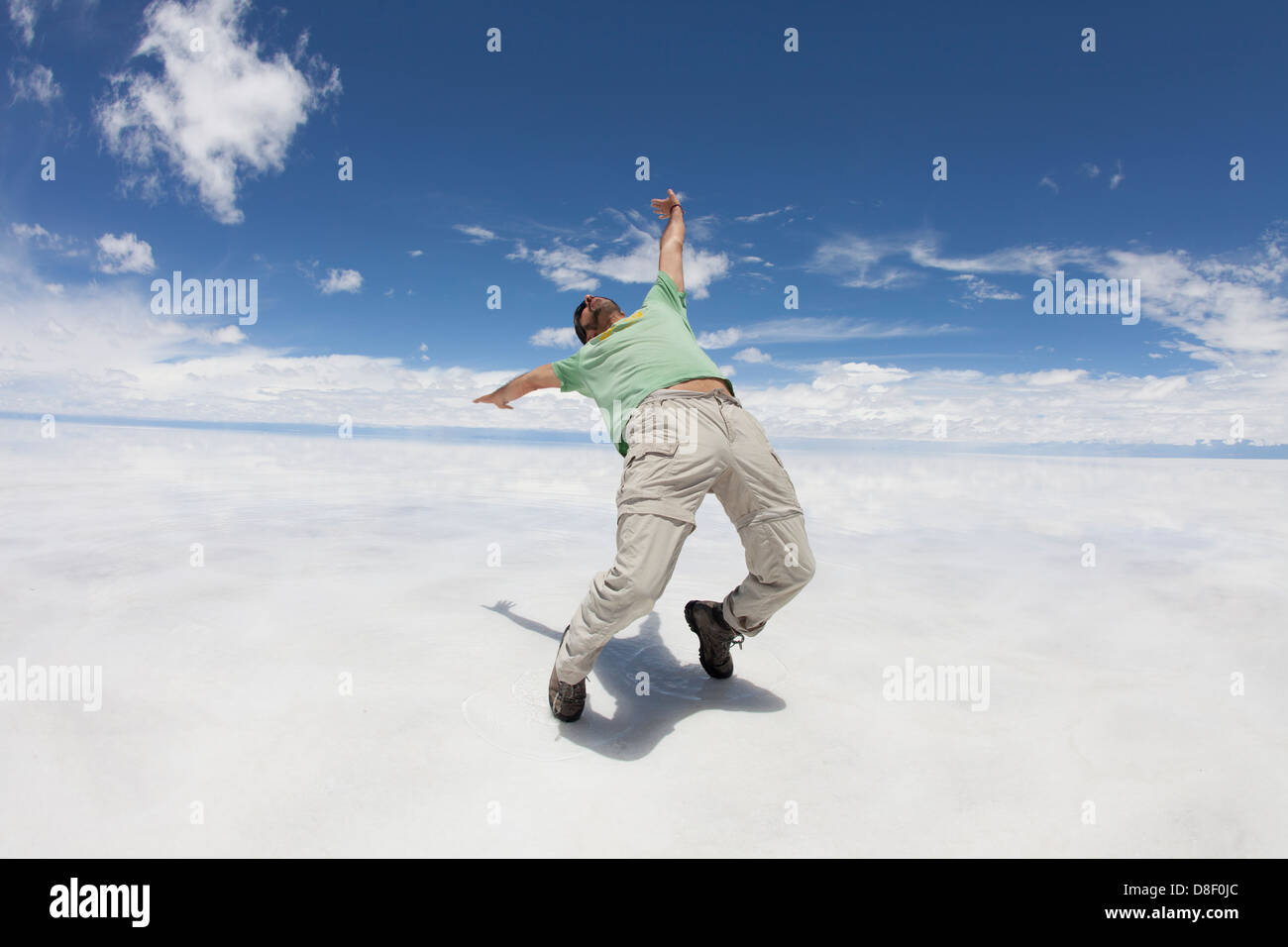 Man bent backwards in bleak white landscape (Salar de Uyuni) Stock Photo