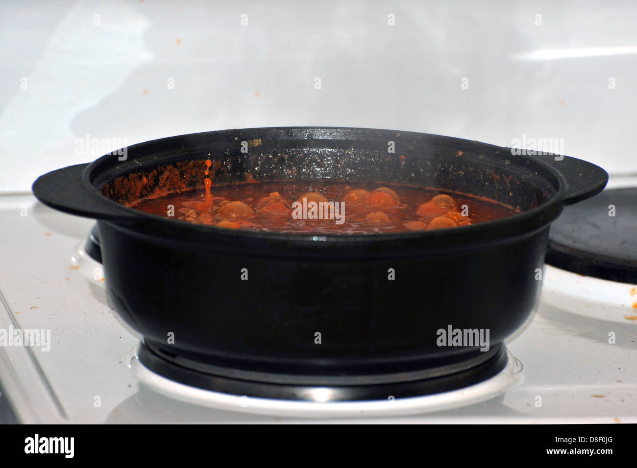 Images of a stew cooking in a cast iron pot on an electric cooker. Stock Photo