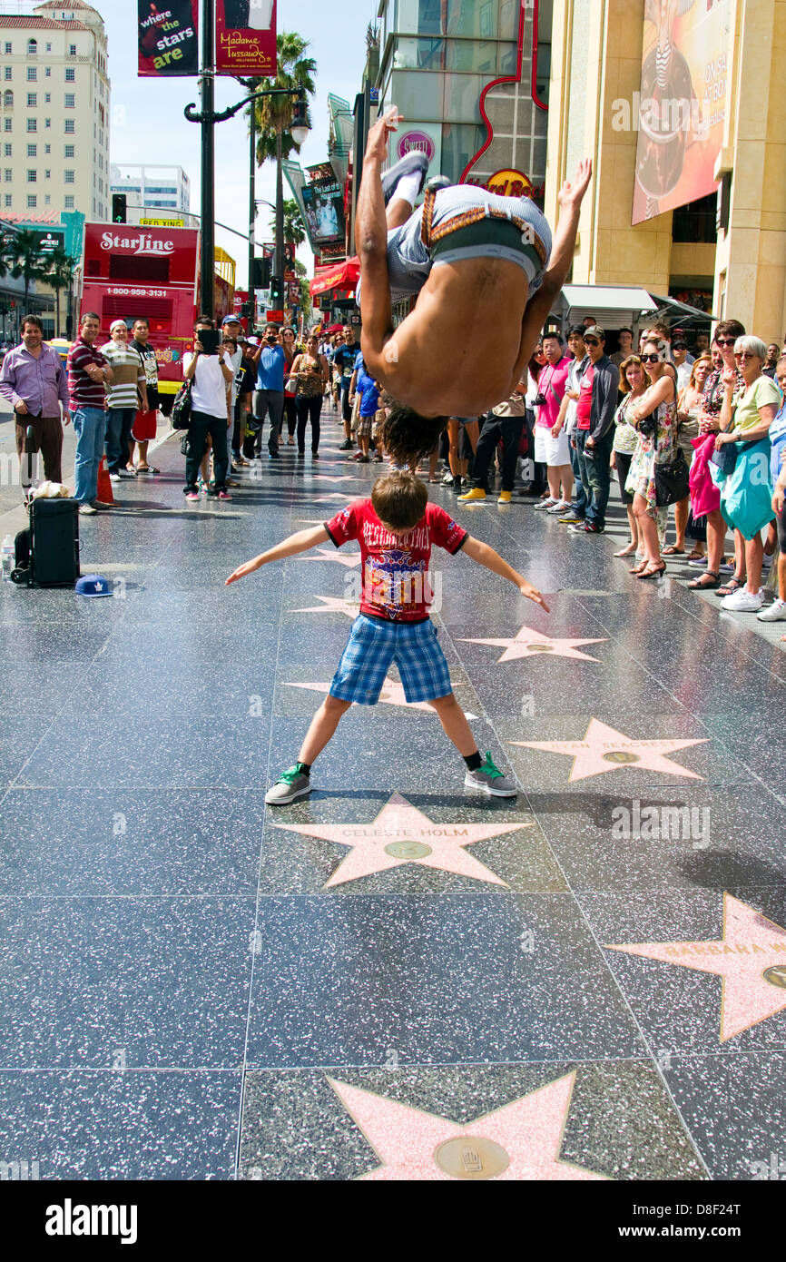 Street performer leaps over tourist while spectators watch on Hollywood Boulevard California Stock Photo