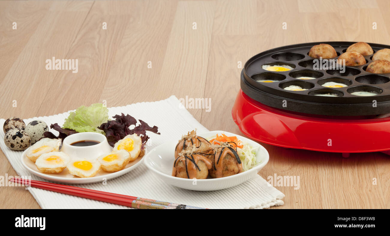 Takoyaki ball cooking machine display with takoyaki and fried eggs Stock Photo