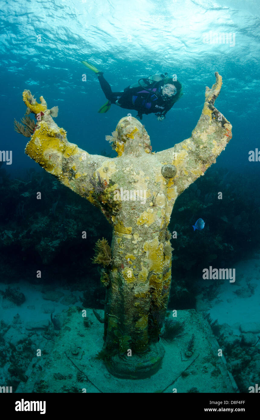 A female scuba diver swims over the famous Christ of the Abyss statue