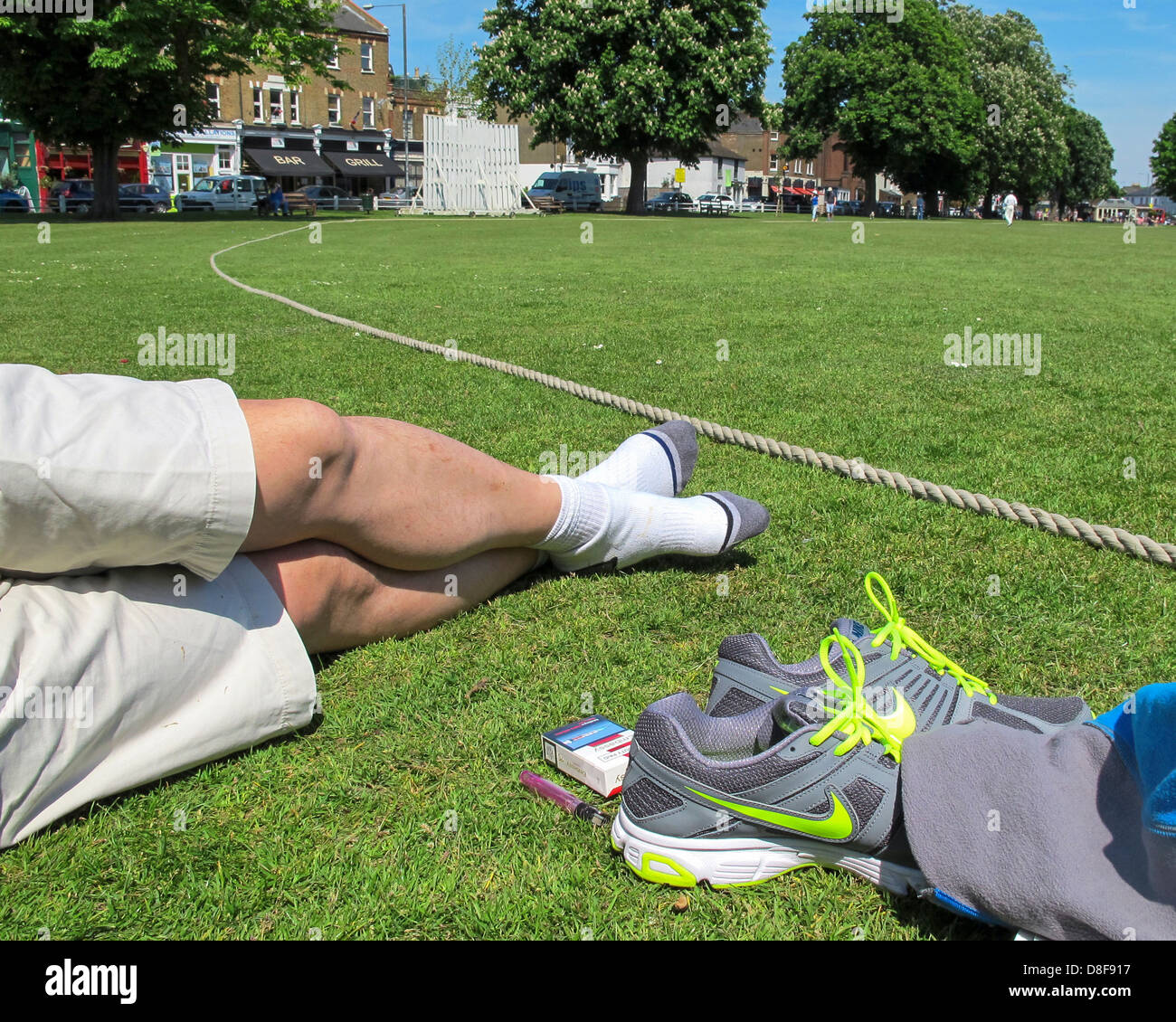 Man relaxing as he watches cricket on Twickenham Green Stock Photo