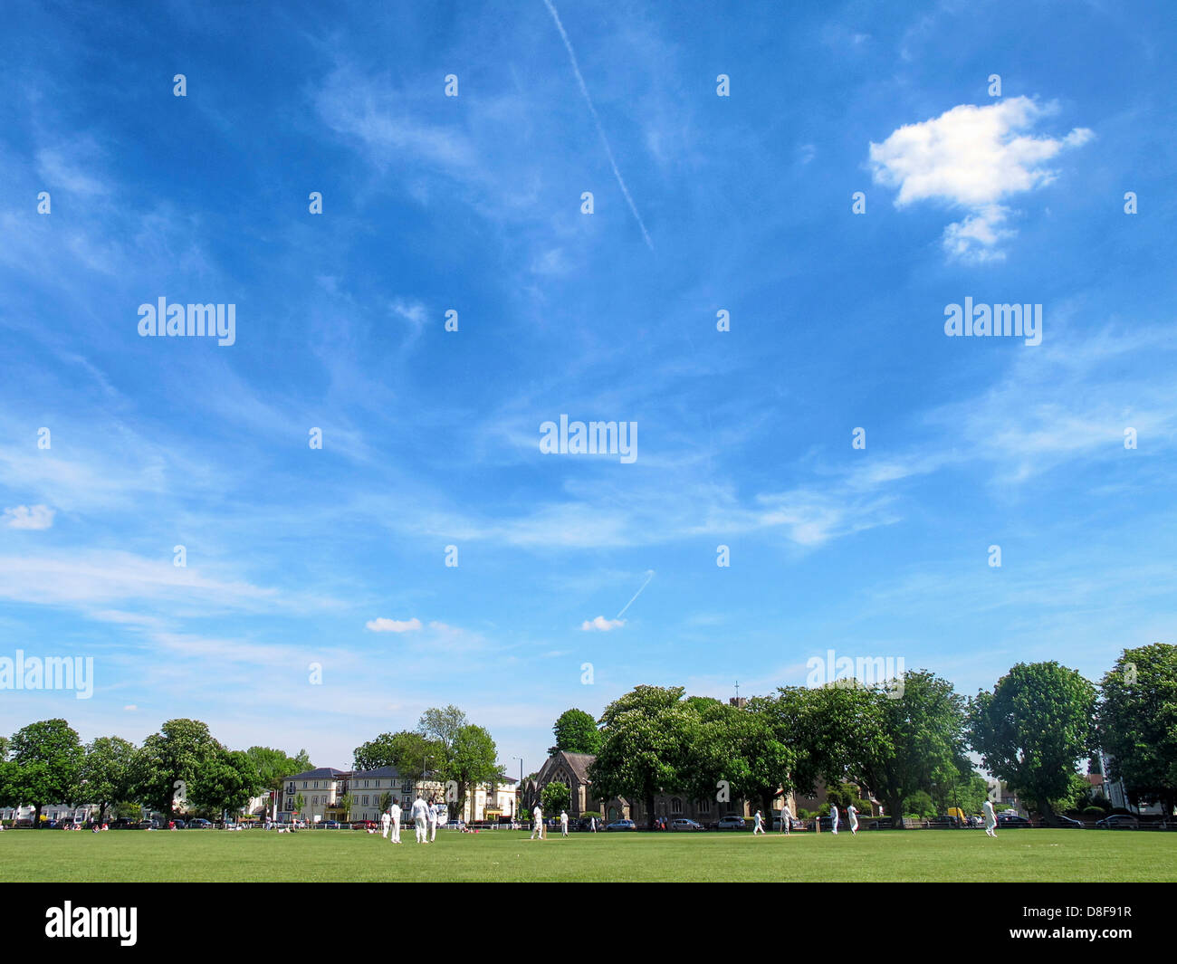 Cricket is played under blue sky on Twickenham Green in Summer Stock Photo