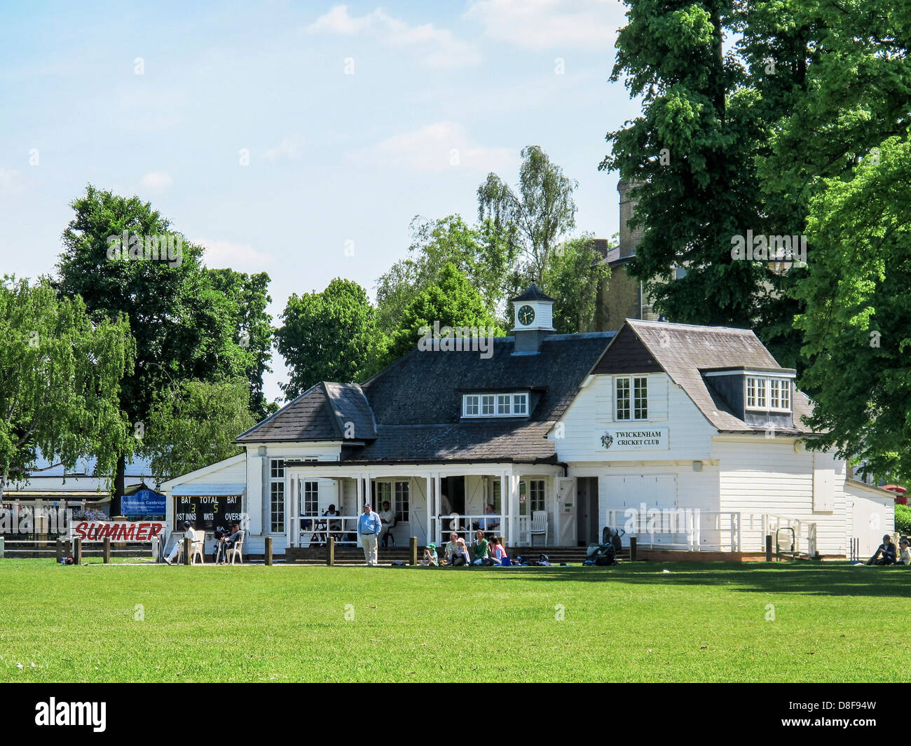 People watching cricket on the green in front of the Twickenham cricket pavilion in Summer Stock Photo