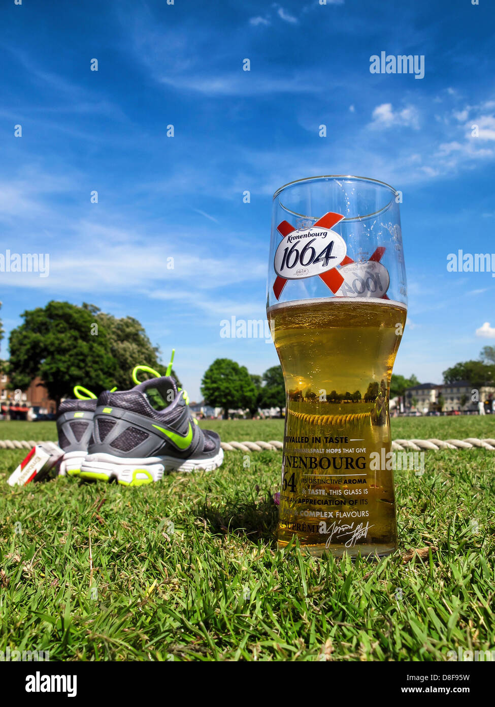 A beer glass, trainers and cigarette pack under a blue sky on Twickenham green in Summer Stock Photo