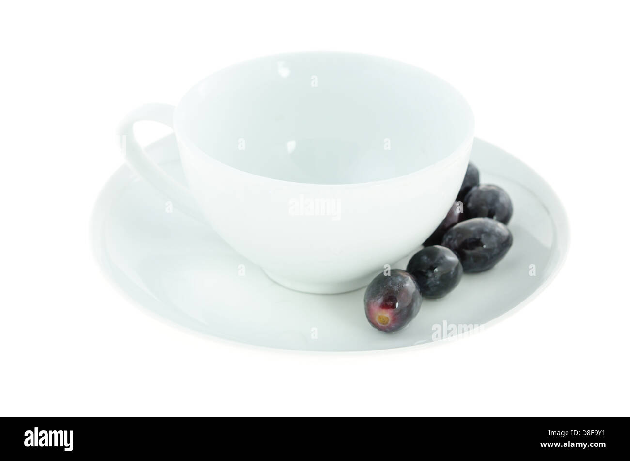 empty white cup and black grapes on plate Stock Photo