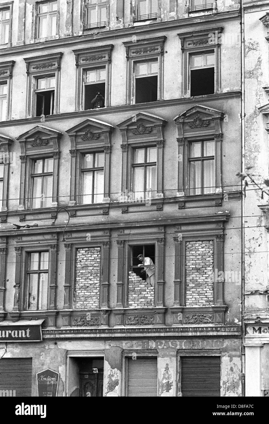 In einem der Grenzhäuser an der Bernauerstraße werden am 1. Oktober 1961 Fenster, die den Blick auf West-Berlin freigeben, zugemauert. Kurz nach dem Mauerbau sind Menschen aus den Fenstern der im Ostteil der Stadt gelegenen Häuser auf die zum Westteil gehörende Bernauer Straße geflüchtet. Am frühen Sonntagmorgen des 13. August 1961 wurde unter der Aufsicht von bewaffneten Streitkräften der DDR mit der Errichtung von Straßensperren aus Stacheldraht und dem Bau einer Mauer begonnen, um den Ostteil Berlins vom Westteil abzusperren. Die Mauer sollte den ständig steigenden Flüchtlingsstrom von Ost- Stock Photo