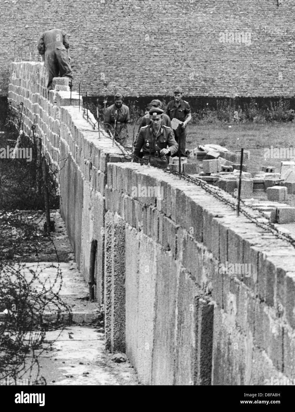Volkspolizisten erhöhen am 9. September 1961 in der Bernauer Straße die Berliner Mauer, um den Sichtkontakt von Ost nach West zu unterbinden. Am frühen Sonntagmorgen des 13. August 1961 wurde unter der Aufsicht von bewaffneten Streitkräften der DDR mit der Errichtung von Straßensperren aus Stacheldraht und dem Bau einer Mauer begonnen, um den Ostteil Berlins vom Westteil abzusperren. Die Mauer sollte den ständig steigenden Flüchtlingsstrom von Ost- nach West-Berlin stoppen Stock Photo